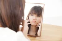 鏡を見て悩む女性